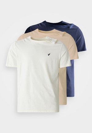 Cuatro camisetas de manga corta en crema, beige claro y dos tonos de azul marino. La tela parece suave y hay un pequeño logo de un pájaro en el pecho de la camiseta crema.