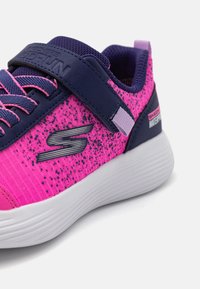 Chaussures Skechers GoRun en rose vif avec des accents bleu marine. Elles présentent un dessus texturé, un logo métallique et une semelle blanche avec un motif de rayures minimal.