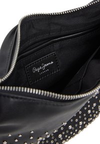 Czarna skórzana torebka z srebrnymi ćwiekami, zamek błyskawiczny oraz wewnętrzna metka z napisem "Pepe Jeans London". Gładka faktura i zorganizowany kształt.