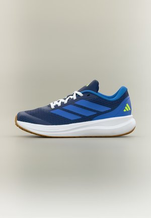 Chaussure de course bleue avec des lacets blancs, une semelle blanche et une semelle extérieure en gomme, avec trois bandes bleues et un logo jaune sur le talon.