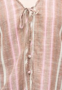 Tissu rayé vertical marron clair et rose avec un lien au niveau de l'encolure et des boutons recouverts de tissu sur le devant.