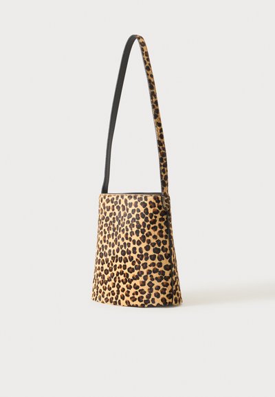Petit sac seau avec une longue bandoulière en motif léopard sur fond clair.