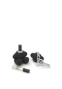 Petit flacon de parfum en forme d'ours noir avec capuchon spray, porte-clés en forme d'ours noir avec chaîne et fermeture argentées, et un petit flacon échantillon de parfum étiqueté KAOS.