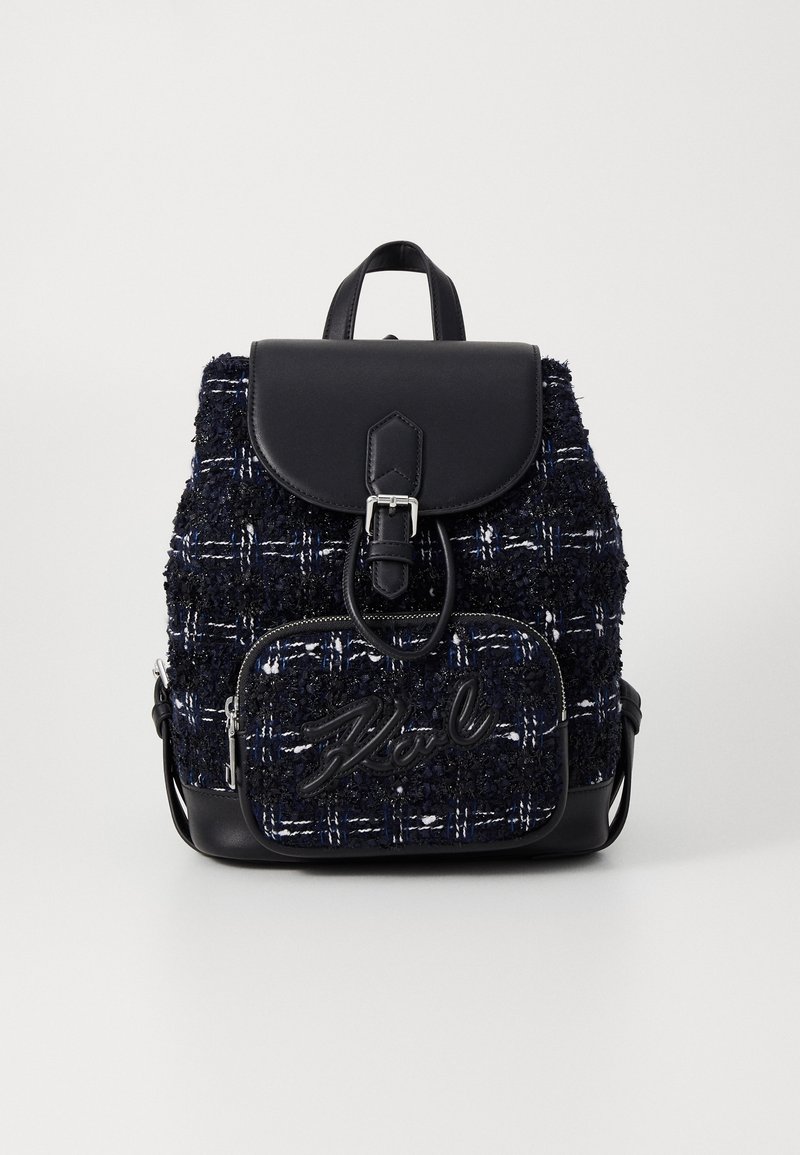 Petit sac à dos texturé noir et bleu marine avec poche avant, fermeture à rabat, détail boucle et poignée supérieure sur fond blanc.