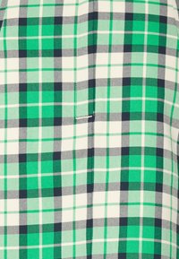 Tecido xadrez verde e azul-marinho com um padrão quadriculado em diferentes tonalidades de verde e branco. Textura suave com linhas em forma de grelha.