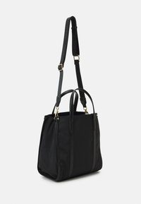 Svart nylon tote-väska med texturerade detaljer, dubbla handtag och ett avtagbart axelband. Har detaljer i guldton.