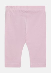 Leggings en coton rose clair avec une taille élastique, présentant une texture lisse et des ourlets cousus. Pas de motifs ni de détails supplémentaires.