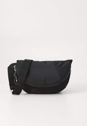 Zwarte nylon crossbodytas met een gebogen ritssluiting en verstelbare schouderriem, liggend op een witte achtergrond.