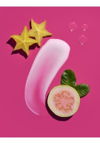 Two starfruit slices, guava half with leaves, pink cream smear, and three clear liquid droplets on bright pink background.