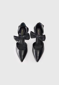 Black leather pointed-toe heels with an ankle strap and bow detail on the front. Smooth texture with a sleek silhouette.