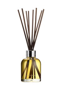 Reed diffuser with a round glass bottle, filled with yellow liquid, and dark brown reed sticks. Silver neck accent; “MADE IN ENGLAND” label.