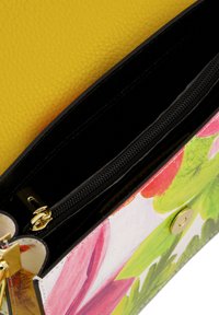 Rechteckige Tasche mit Blumenmuster, die über ein gelbes strukturiertes Leder-Außenmaterial, einen schwarzen Reißverschluss und goldene Hardware-Details verfügt.