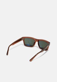 Ochelari de soare pătrați cu rame din plastic translucid de culoare maro, lentile de un verde închis și brate elegante de culoare maro cu un detaliu subtil de accent.