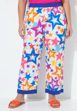 Kleurrijke losse broek met sterrenprint, blauwe elastische tailleband en boorden, gedragen met fel koraalkleurige slidesandalen, getoond van taille tot voeten.