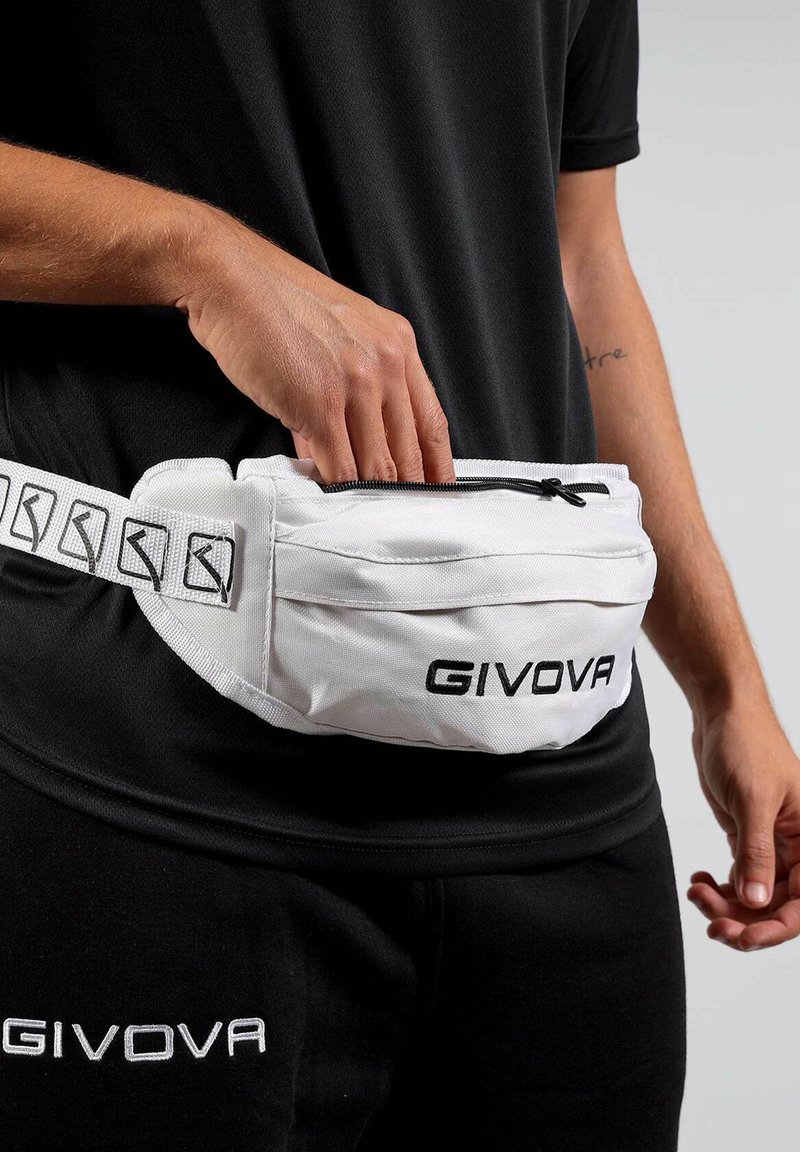 Mano nella tasca con zip di una borsa a vita bianca GIVOVA indossata sopra abbigliamento sportivo nero GIVOVA all'anca di una persona.