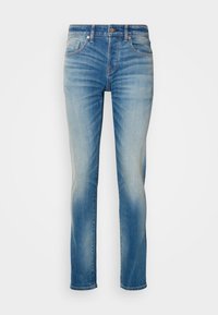 Helle blaue Denim-Jeans mit geradem Schnitt, ausgestattet mit fünf Taschen und subtilen Abnutzungsspuren an den Oberschenkeln. Metallknopf- und Reißverschluss.