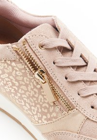 Zapatilla deportiva de ante rosa con detalles en estampado de leopardo dorado, que cuenta con cierre lateral de cremallera, diseño de cordones y acabado texturizado. Suela de goma blanca.