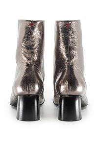 Stivaletti alla caviglia in bronzo metallico con una finitura testurizzata, dotati di tacco a blocco nero e dettagli rossi nella cucitura superiore.