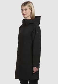 Black waterproof coat with a hood, long sleeves, zip closure, and side pockets. Smooth texture with minimal hardware accents.
