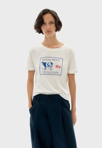 Witte katoenen T-shirt met een blauwe grafische print van een koe en de tekst "Thinking MUUU 500 gr" op de voorkant. Korte mouwen en een ontspannen pasvorm.