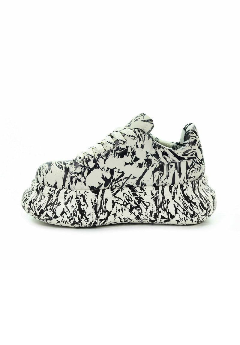 Masywne sneakersy z czarno-białym wzorem abstrakcyjnych plam farby i grubą, teksturowaną podeszwą, widziane z boku.
