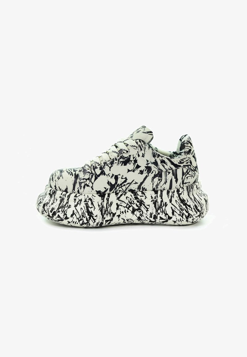 Masywne sneakersy z czarno-białym wzorem abstrakcyjnych plam farby i grubą, teksturowaną podeszwą, widziane z boku.