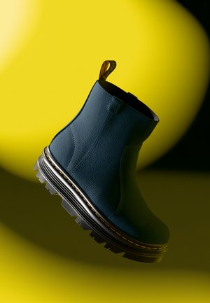 Blå lær ankle boot med teksturert overflate, tykk svart gummisåle og gul søm, med en pull tab på baksiden.