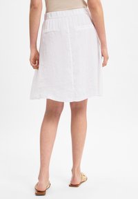 Valkoinen pellava hame, jossa on joustava vyötärö. Hame ulottuu juuri polven ylle. Siinä on kaksi takataskua ja hieman levenevä siluetti.