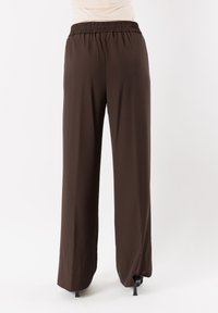 Pantaloni marroni a gamba larga con vita elastica. Realizzati in un tessuto morbido, caratterizzati da una vestibilità comoda e dettagli minimi.