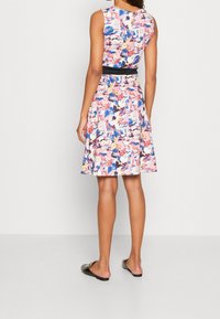 Robe fleurie avec un corsage ajusté et une jupe évasée aux tons rose, bleu et crème. Taille noire et design sans manches.