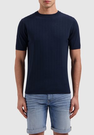 Marineblauw T-shirt met korte mouwen, geribbelde stof en een ronde hals, gecombineerd met lichtblauwe denimshorts met opgerolde zoom. Gladde textuur en aansluitend ontwerp.