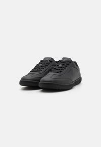 Svart sneakers laget av glatt skinn med en teksturert gummisåle, med rund tupp og klassisk snøring.