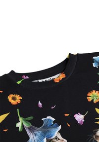 Mustriline kangas erksate lillemusteritega ja osaliselt nähtava kassi näoga suure sinise lille all lähedal ümara kaelusega.