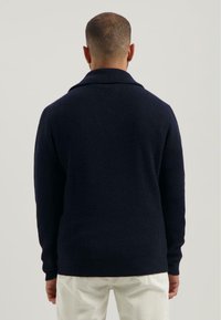 Marineblauwe geribbelde gebreide trui met een sjawlboord, lange mouwen en een relaxte pasvorm, met textuurstof voor extra warmte.