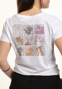 Bílý tričko s mřížkou devíti ilustrací karikatur zvířat v různých barvách a výrazech na zadní straně. Bavlněný materiál, volný střih.