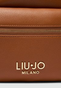 Sac en cuir marron texturé avec une fermeture éclair dorée et le logo de marque "LIU·JO MILANO" embossé à l'avant.