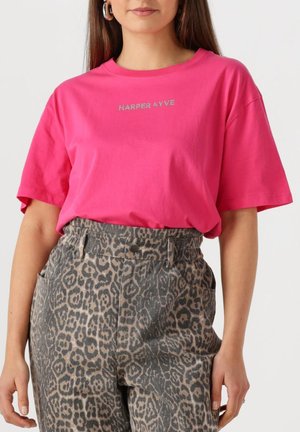 Felroze katoenen t-shirt met een ronde halslijn en korte mouwen, met "HARPER & YVE" in zilveren studs. Gecombineerd met grijze pantoffels met luipaardprint.