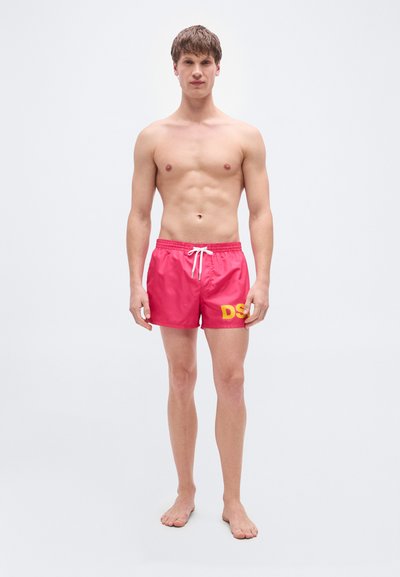 Ροζ μαγιό βερμούδα με ελαστική μέση και ρυθμιζόμενο κορδόνι μπροστά, με έντονη κίτρινη εκτύπωση "DS" στον αριστερό μηρό. Λείο υλικό.
