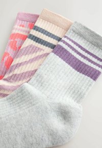 Tri para bombažnih nogavic: roza s vzorcem, svetlo bež s črtami in sive s vijoličnimi črtami. Struktuiran zaključek, raznolike barve.