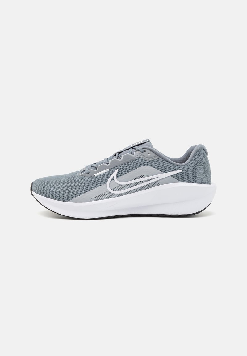 Chaussures de sport grises avec un dessus en maille respirante, logo swoosh blanc, semelle intermédiaire blanche épaisse et semelle en caoutchouc noir texturé.