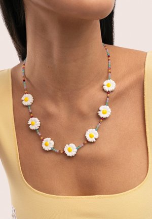 Necklace with white daisy beads and multicolored small beads on a woman wearing a yellow tank top.