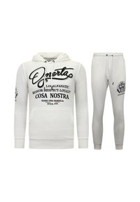 Witte hoodie en bijpassende joggers, met zwarte tekst en graphics. Het materiaal lijkt zacht met ribgebreide manchetten en een tailleband.