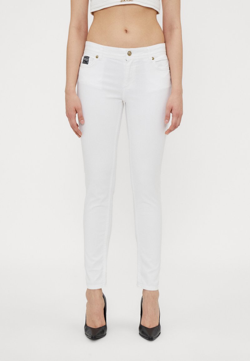 Witte skinny jeans van stretchdenim, met voorzakken, een ritssluiting en gouden accenten. Eenvoudig ontwerp met een slim fit.