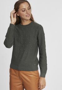 Grijze bobble-knit trui met een ronde halslijn, geribde zoom en boorden, en een getextureerd stippenpatroon over de hele trui.