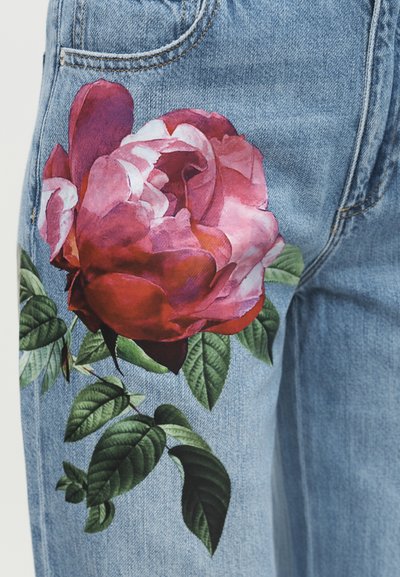 Džínsové nohavice s veľkou, detailnou potlačou červenej a ružovej ruže a zelených listov na oblasti stehna.