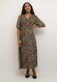 Maxi kjole med leopardmønster i beige og sort med korte ærmer, knaplukning foran og afslappet pasform. Båret med sorte sko.
