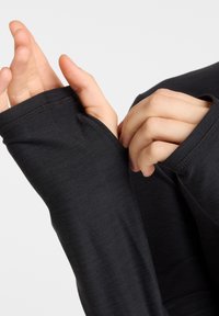 Black long-sleeve shirt with extended cuffs partially covering hands, made of soft fabric, featuring a smooth texture and fitted design.