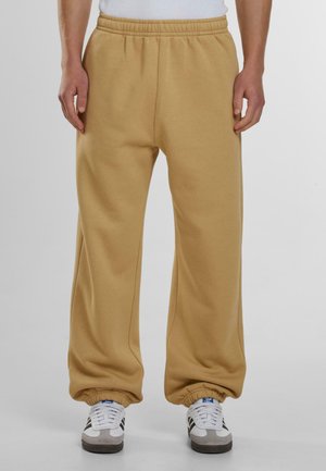 Beige sweatpants with an elastic waistband and cuffed hems. Made of soft fabric, featuring a relaxed fit and minimal stitching details.