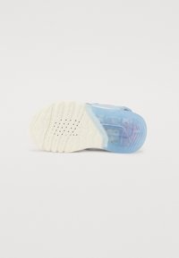 Semelle de chaussure de sport bleue avec une base en caoutchouc blanc texturé, comprenant une section transparente bleue et de petits trous de ventilation pour la respirabilité.