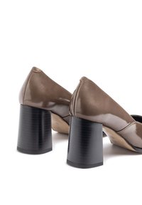 Scarpe con tacco a blocco in pelle verniciata marrone con una finitura lucida, punta arrotondata e tacchi neri solidi, caratterizzate da una texture liscia.